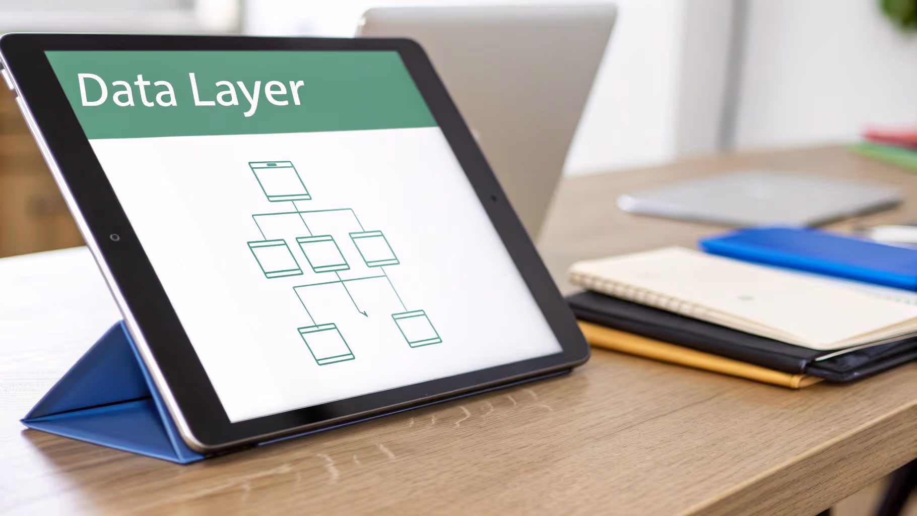 A tablet displays 'Data Layer' with a flowchart diagram on a wooden desk alongside notebooks.