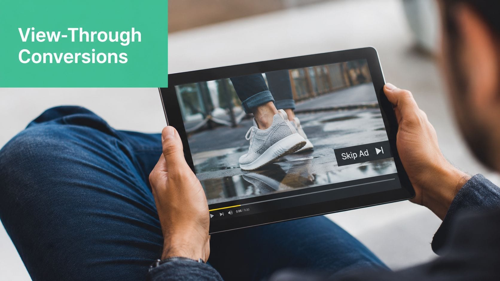 A person holding a tablet showing a video advertisement with a skip ad button overlay.