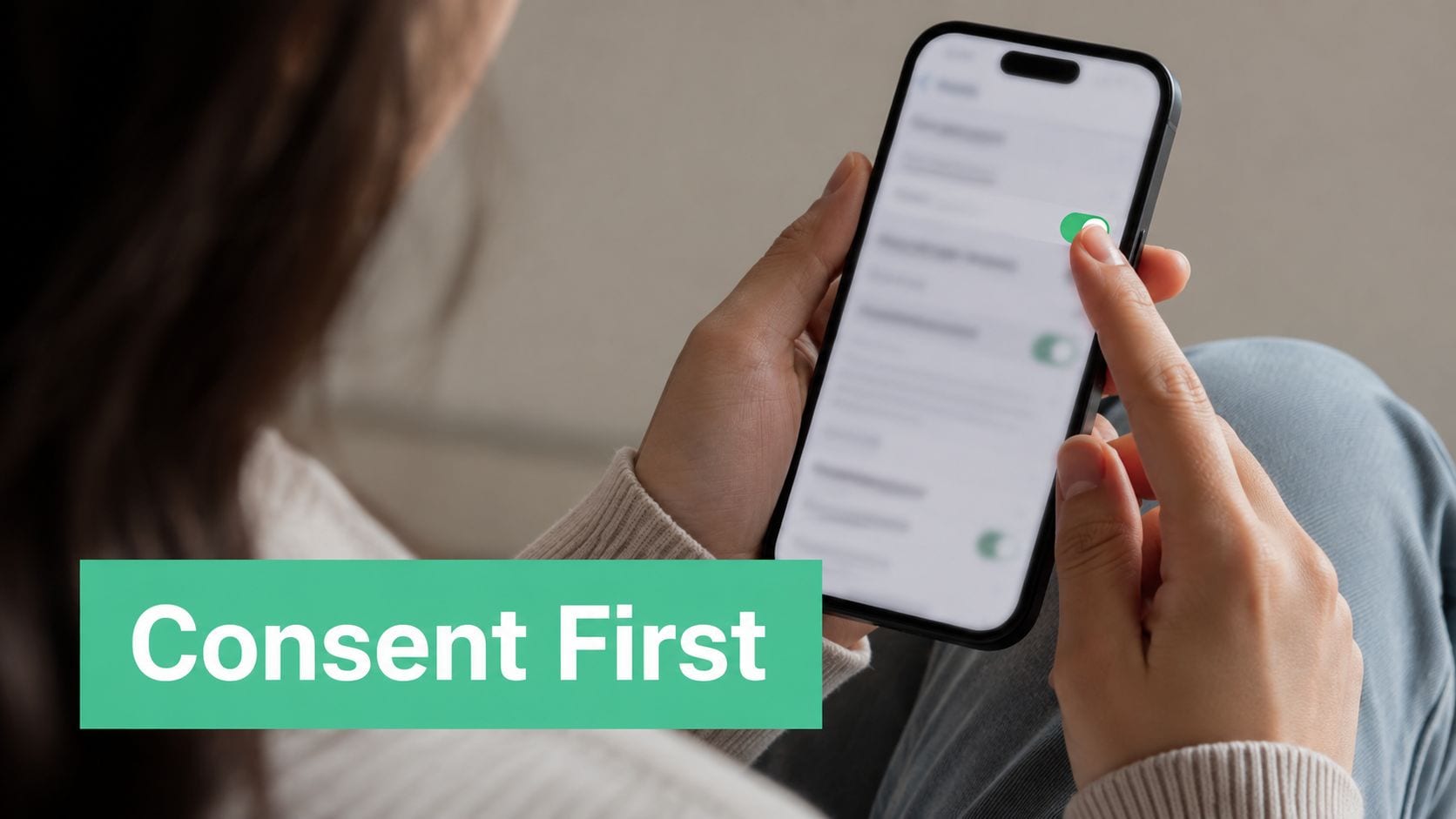 A person holding a smartphone and toggling privacy settings in a mobile app, focusing on user consent.